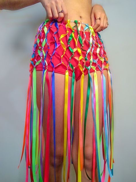 a woman is wearing a colorful skirt with streamers on the bottom, and has her hands in her pockets