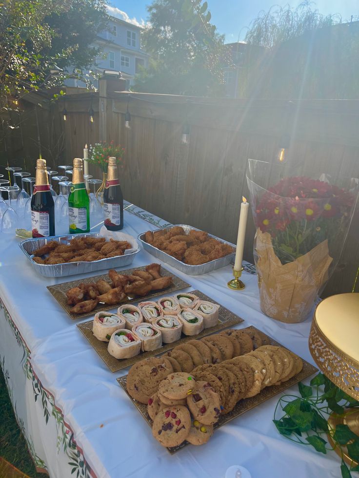 a table with food and drinks on it in front of a fenced in area