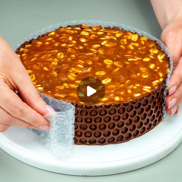 two hands holding a cake on top of a white plate