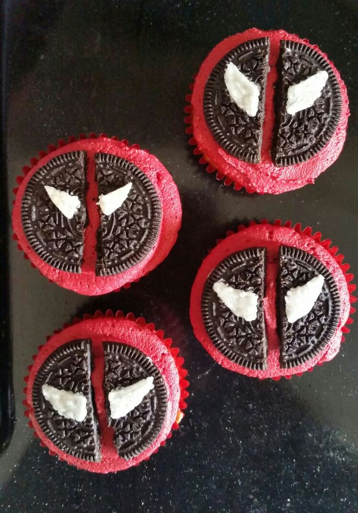 four cupcakes with red frosting and white icing in the shape of wings