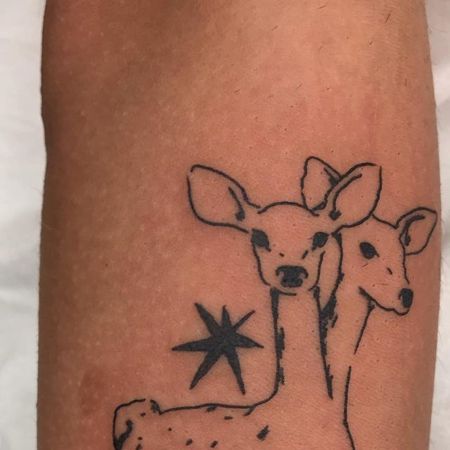 a small tattoo on the leg of a person with a deer and star in it