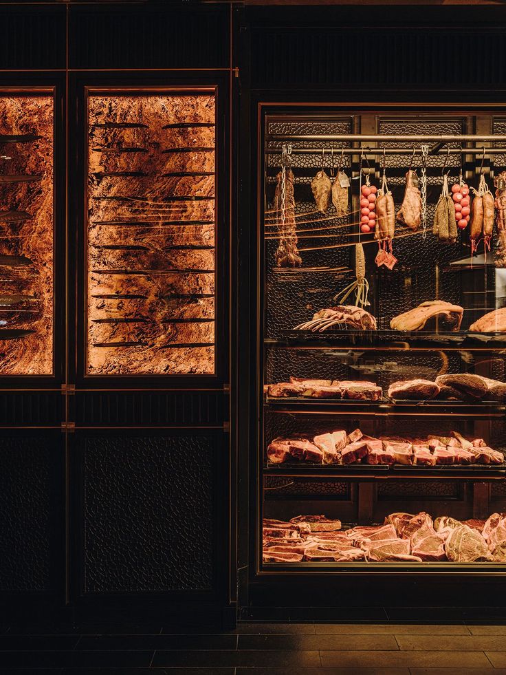 meats are displayed in the window of a butcher's shop at night time