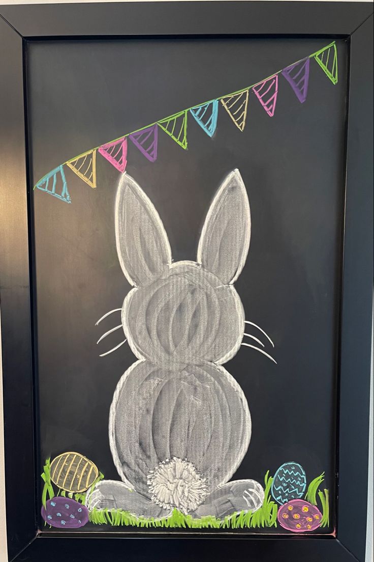 a chalk drawing of a bunny sitting in front of an easter egg and bunnies