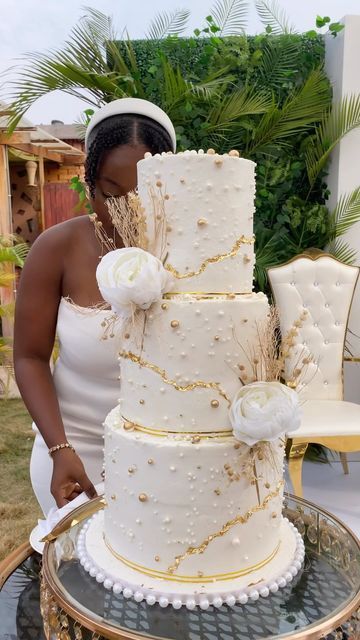 a woman in white dress standing next to a large cake on top of a table