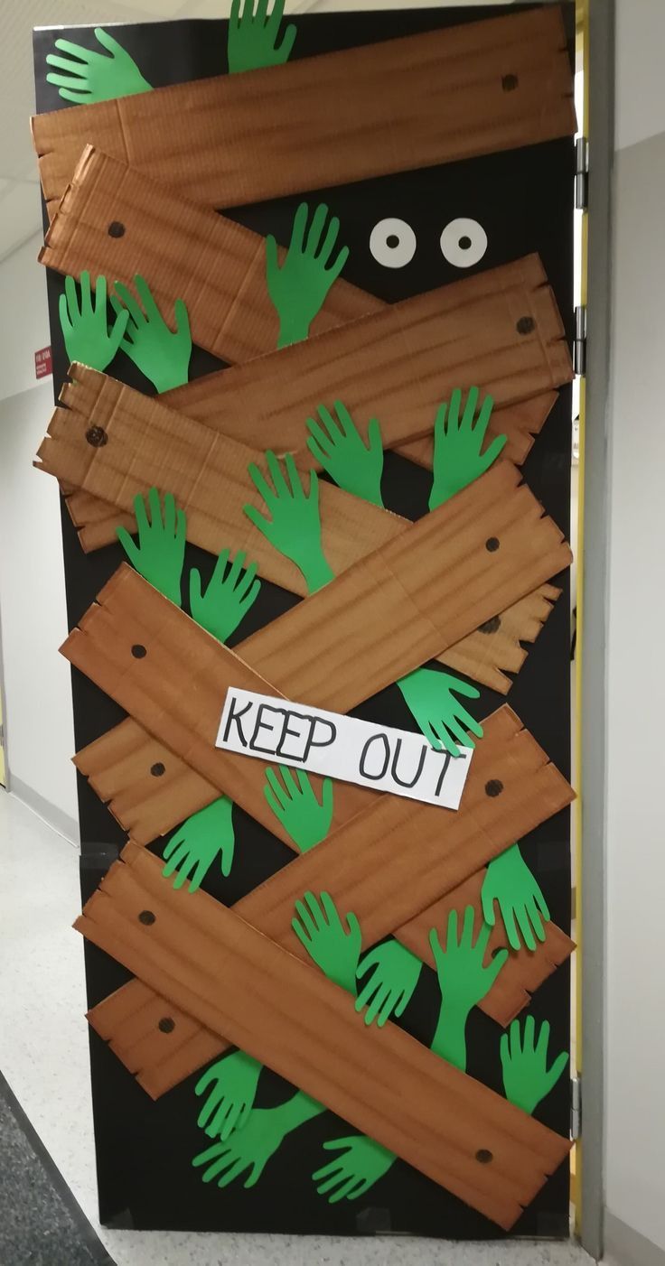 a door decorated with green handprints and cutouts that says keep out on it