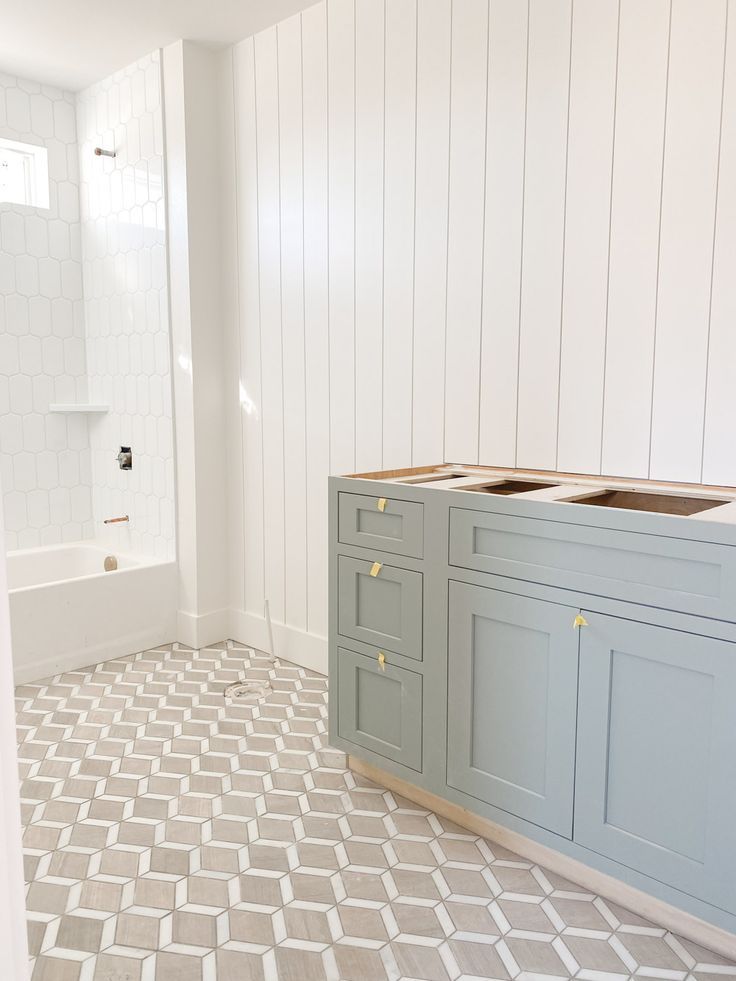 an empty bathroom with white walls and blue cabinets in the corner, next to a tiled floor