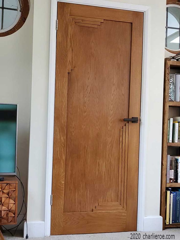 a wooden door in a living room next to a book shelf with books on it