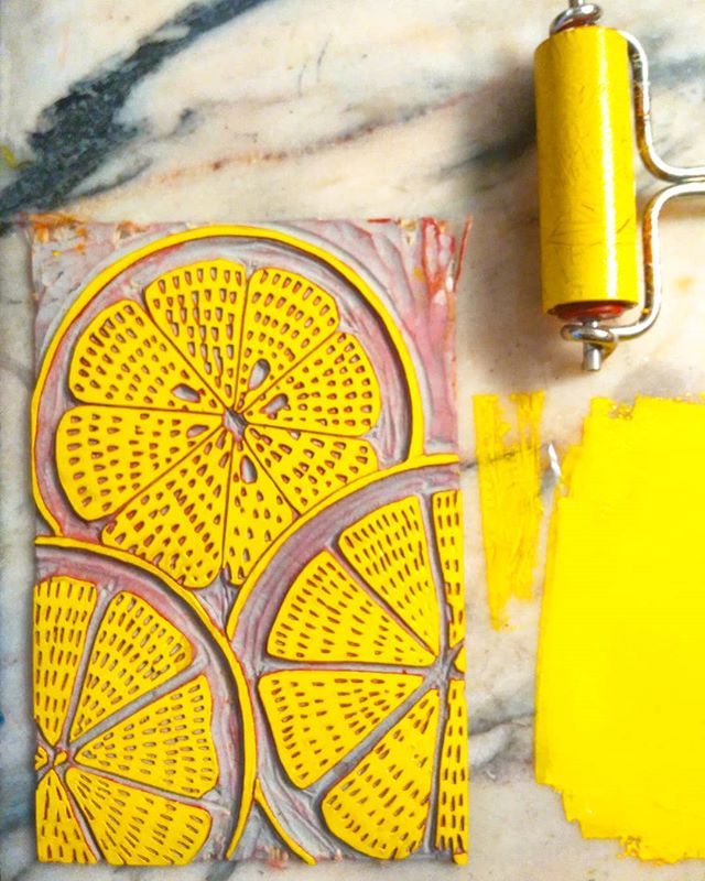 a yellow piece of art sitting on top of a marble counter next to paint rollers