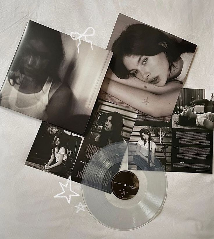 an album and two cds are laying on a white sheet with black and white photos