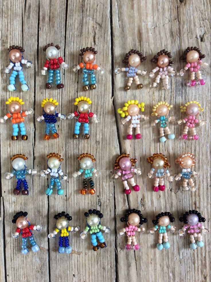 many small dolls are arranged on a wooden surface, including one with an earring in the middle