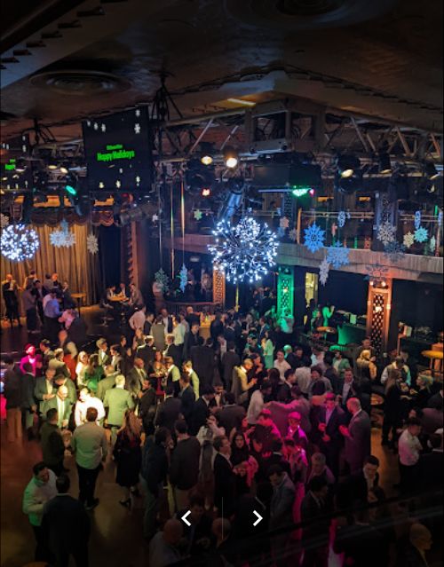 a group of people standing around in a room with lots of lights on the ceiling