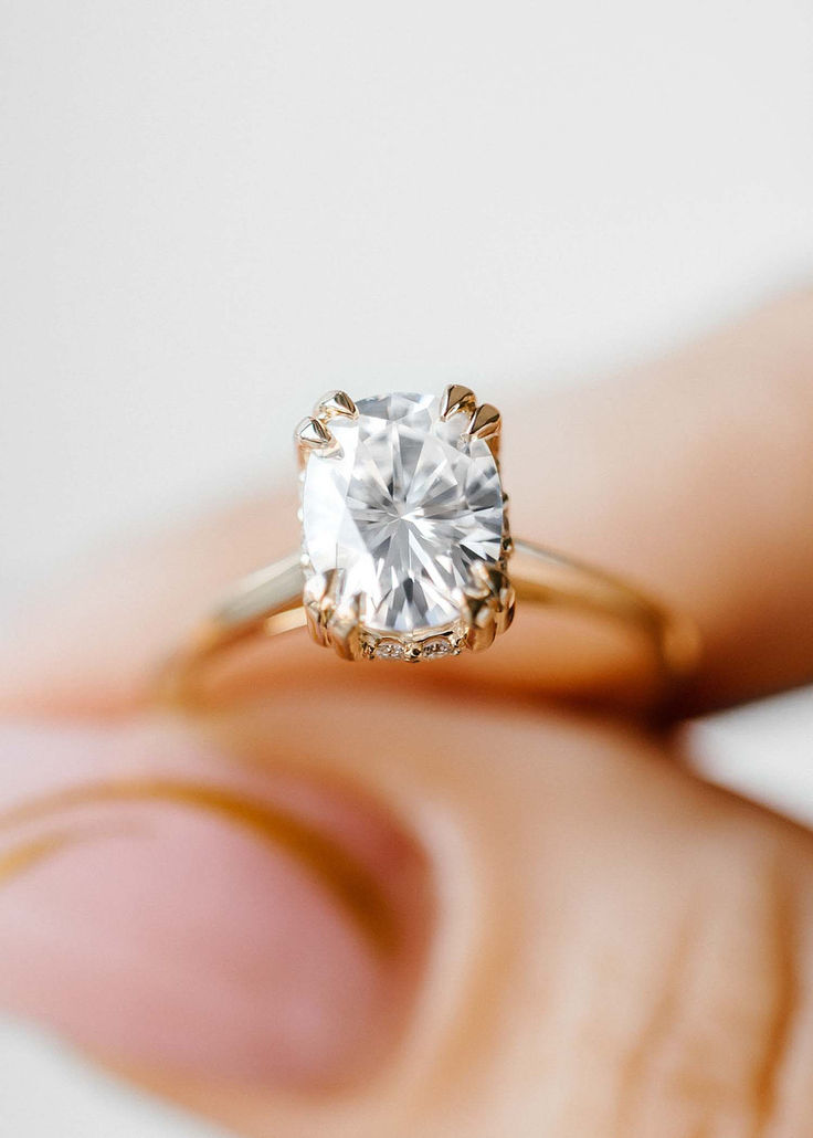 a woman's hand holding an engagement ring with a diamond in the center, on top of her finger