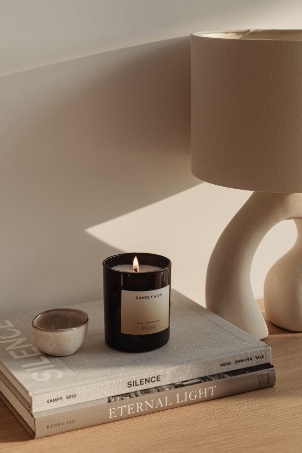 a candle sitting on top of a book next to a white vase and lamp shade