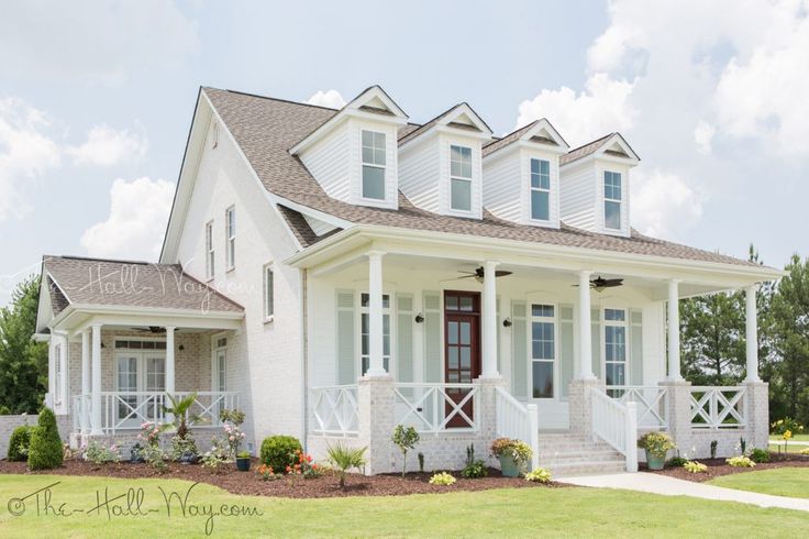 a white two story house with porches and windows on the first floor is shown