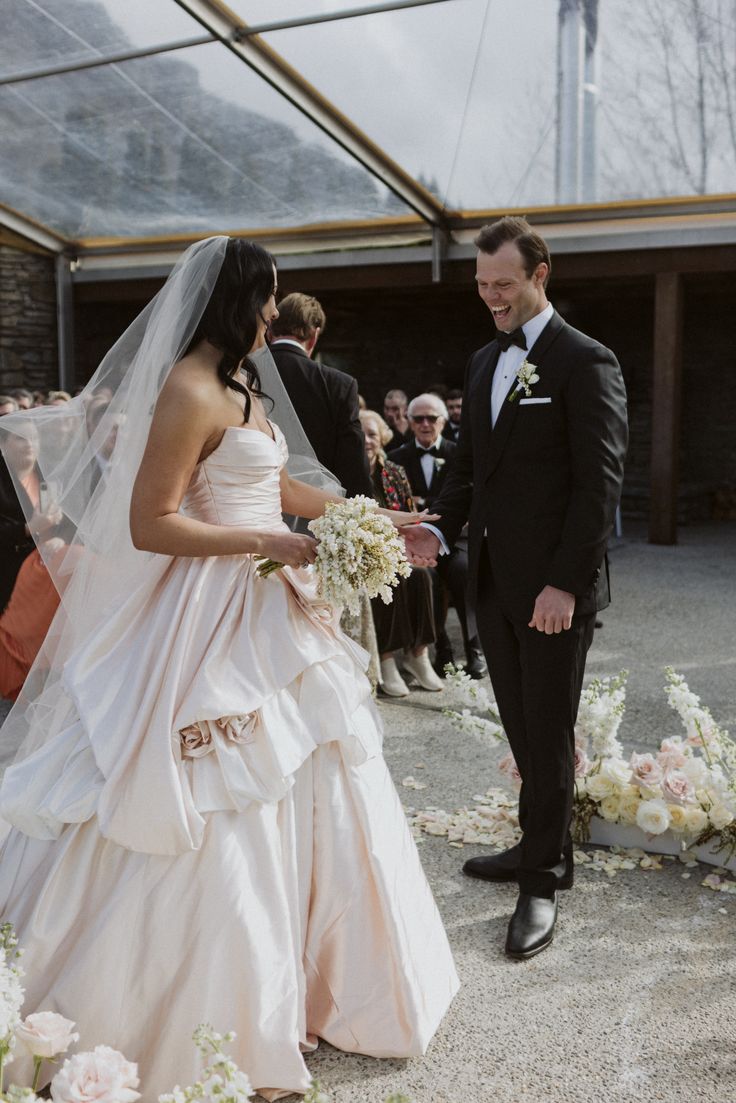 a bride and groom standing in front of a group of people