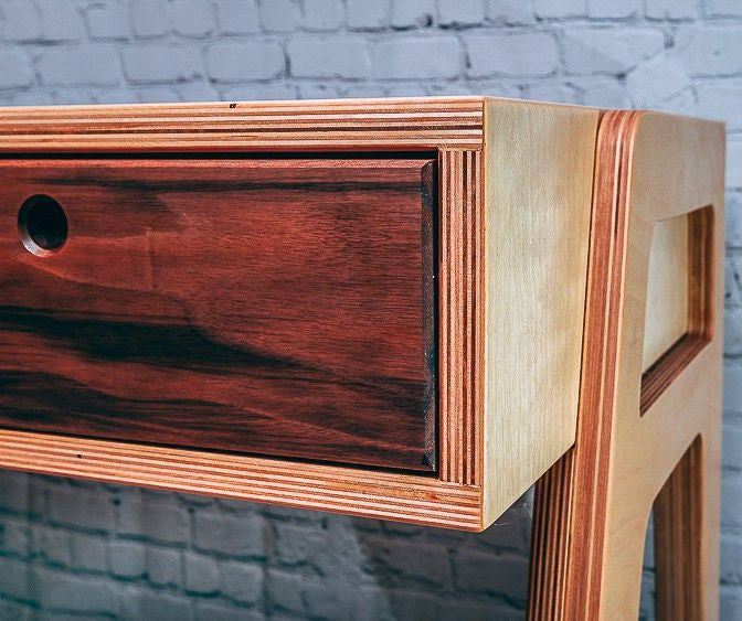 a close up of a wooden table with drawers on it's sides and a brick wall in the background