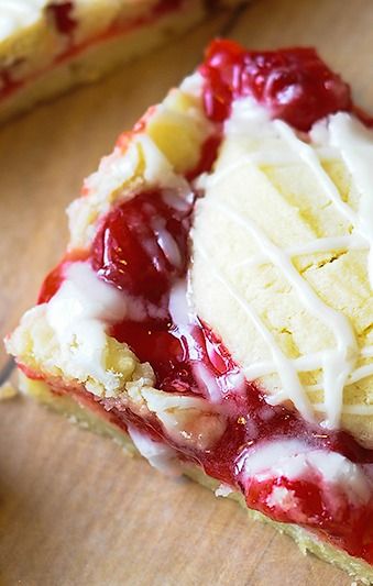 a piece of pie with white icing and strawberries on it sitting on a cutting board