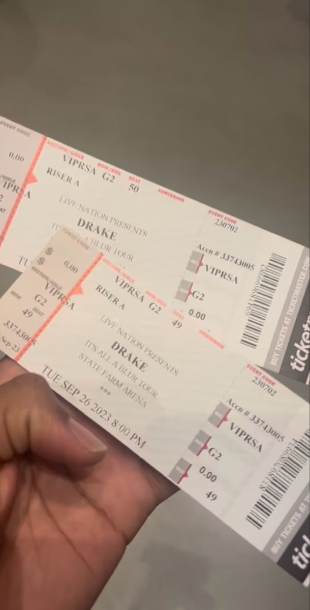 two tickets are being held up in front of someone's face and the other hand is holding them