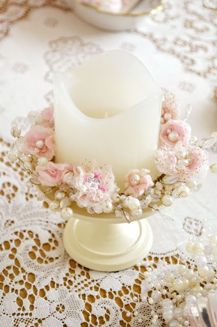 a white candle sitting on top of a table next to a lace covered table cloth