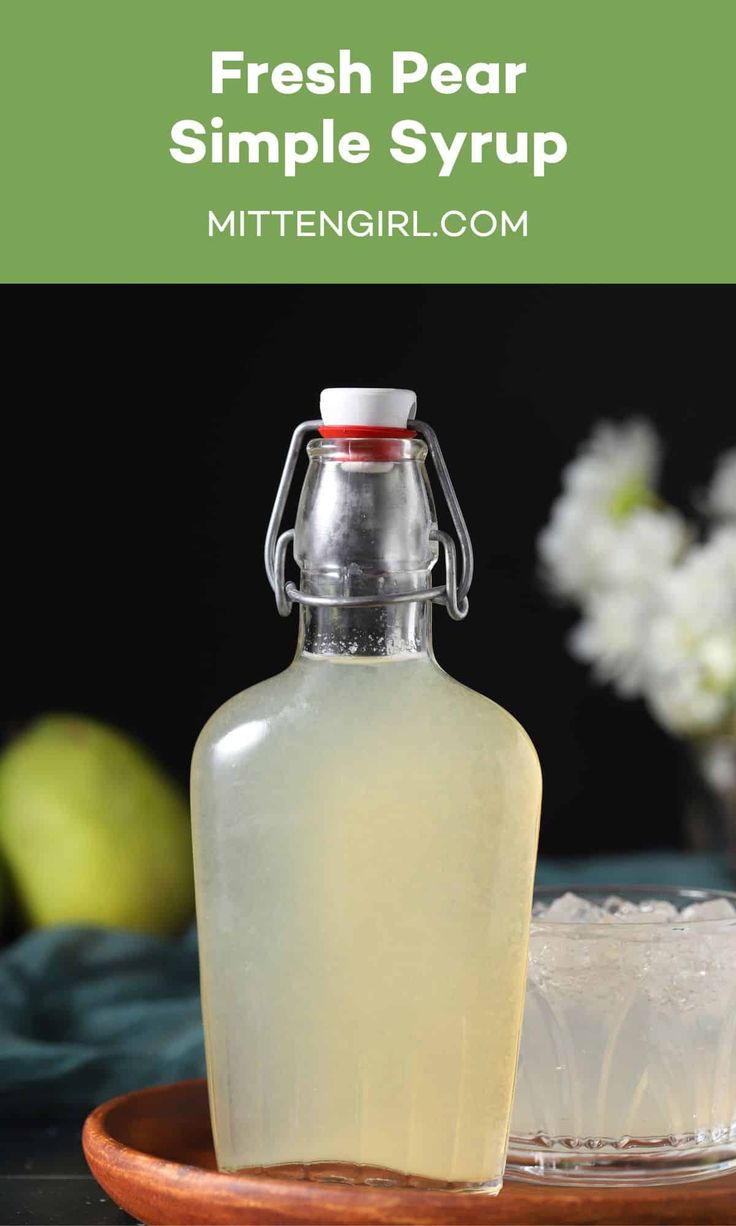 a bottle of fresh pear simple syrup on a plate with ice and apples in the background