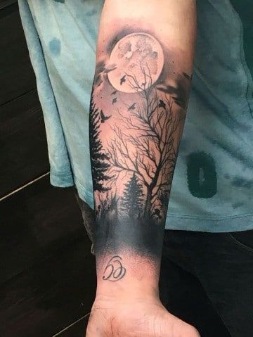 a man's arm with a full moon and tree tattoo on the left forearm