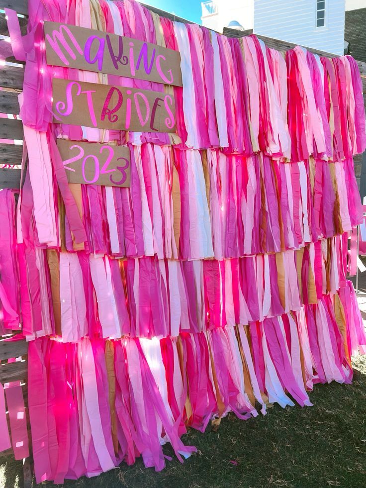 pink and gold streamers are hanging on a wooden fence with a sign that says, don't stop to sess