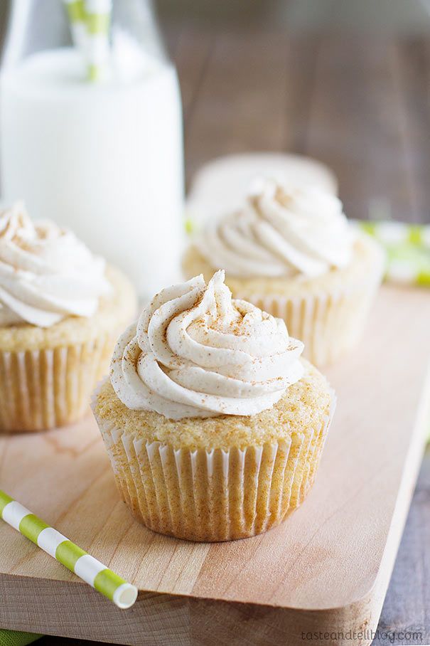 three cupcakes with white frosting on a cutting board