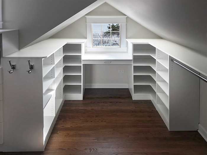 an attic bedroom with white shelving and wood floors