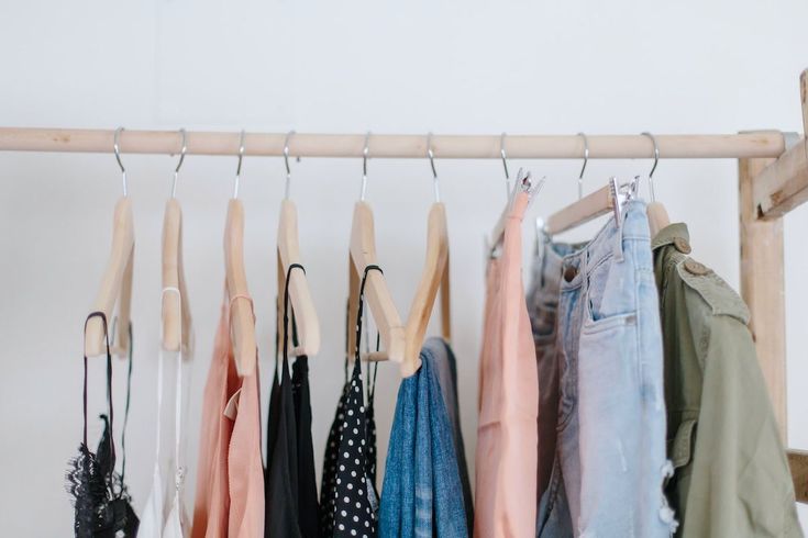 clothes hanging on a rack in front of a white wall