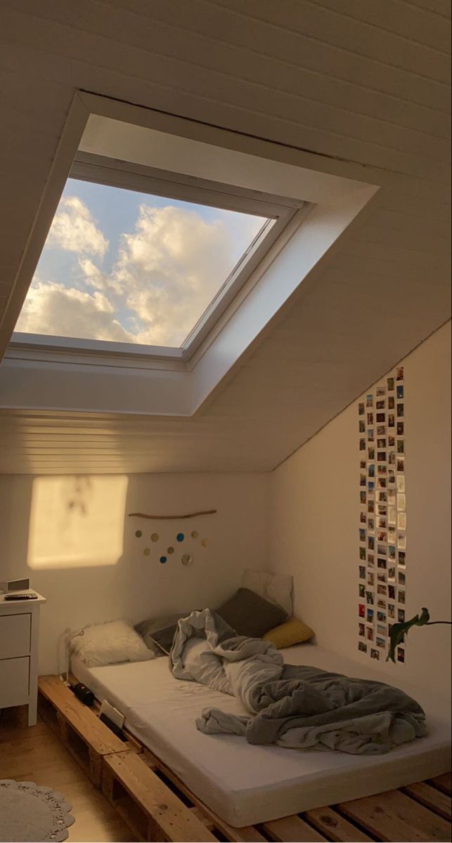 a bed sitting under a skylight in a room with wooden pallets on the floor