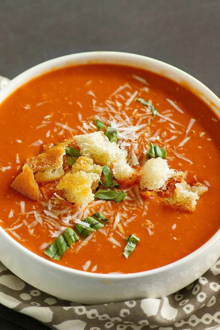 a bowl of tomato soup with croutons and parmesan cheese