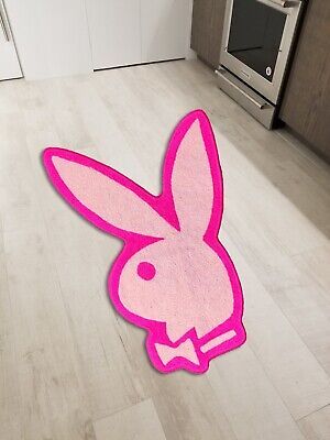 a pink rabbit rug in the middle of a kitchen with an oven and microwave behind it