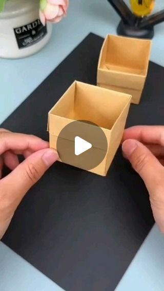 two hands holding open boxes on top of a table