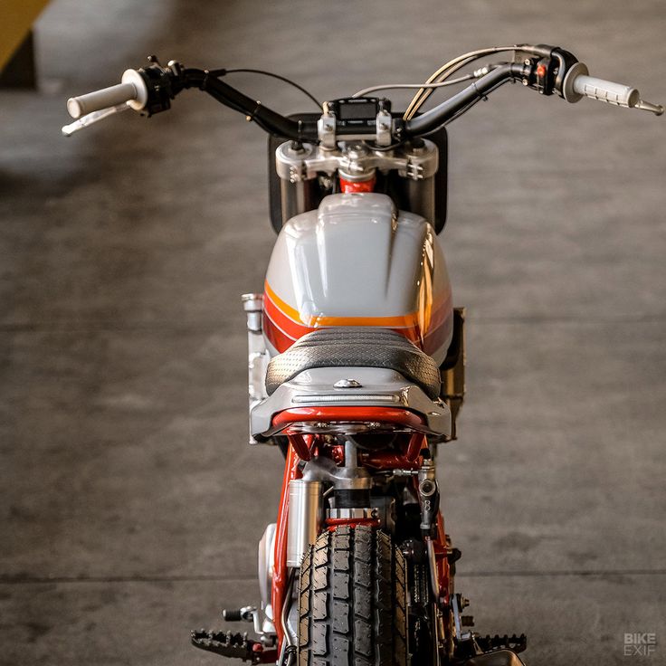 an orange and white motorcycle parked in a garage