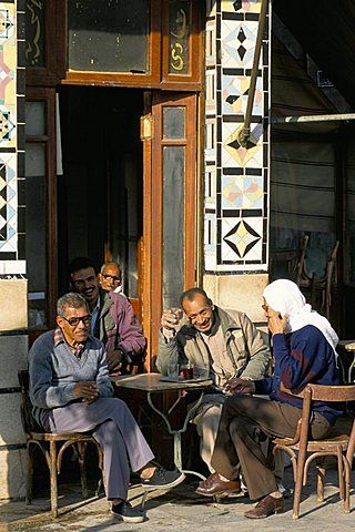 several people sitting at small tables in front of a building