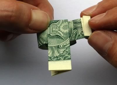 two hands are holding an origami piece of money