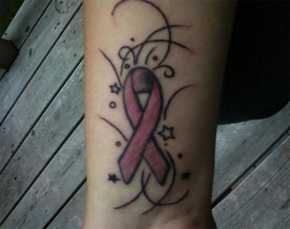 a woman's foot with a pink ribbon tattoo on it