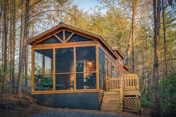 a small cabin in the woods with stairs leading up to it's second floor