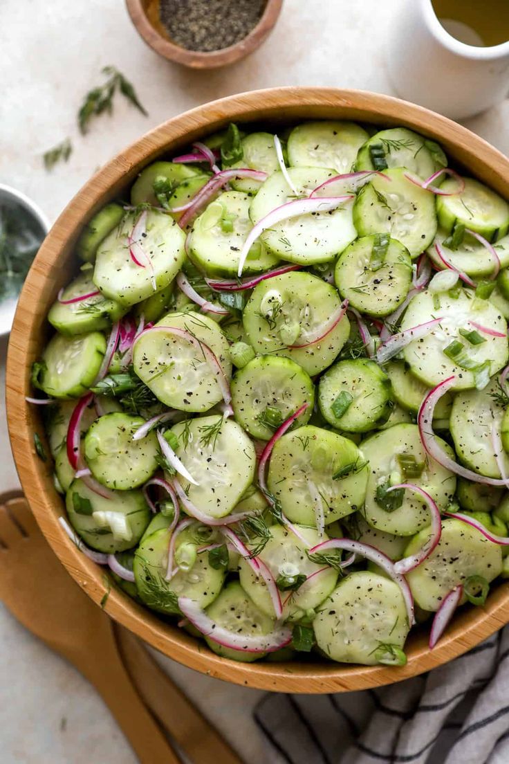 a wooden bowl filled with cucumbers and onions