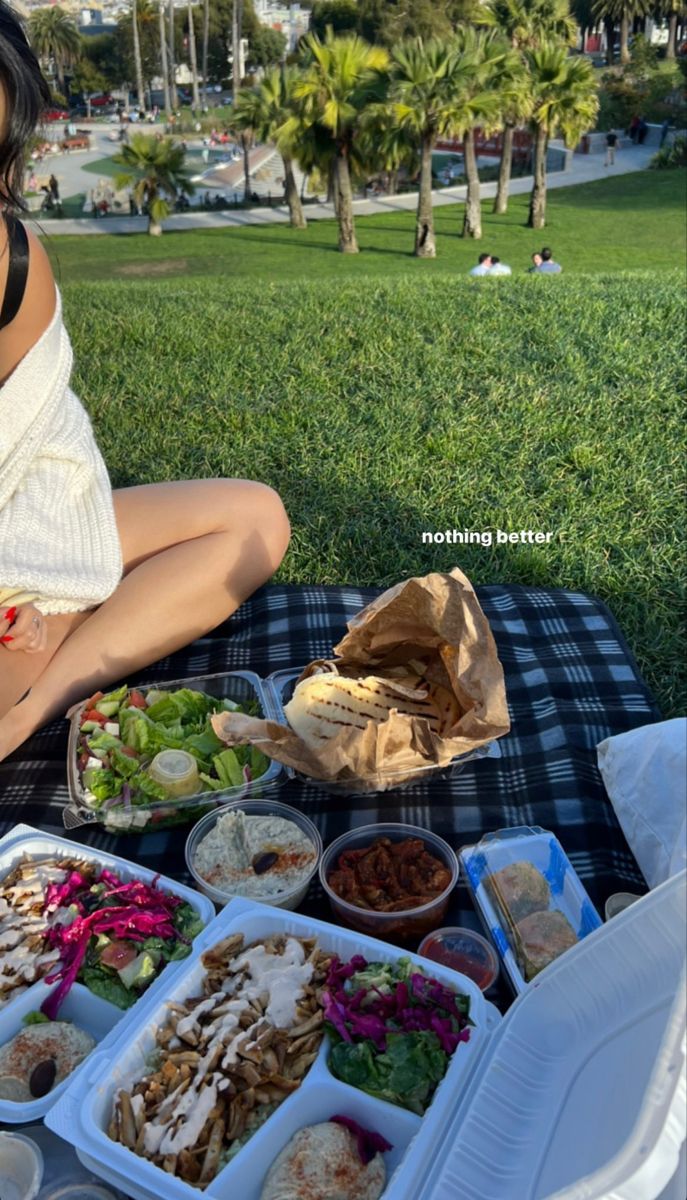 a woman sitting on the grass with food in front of her