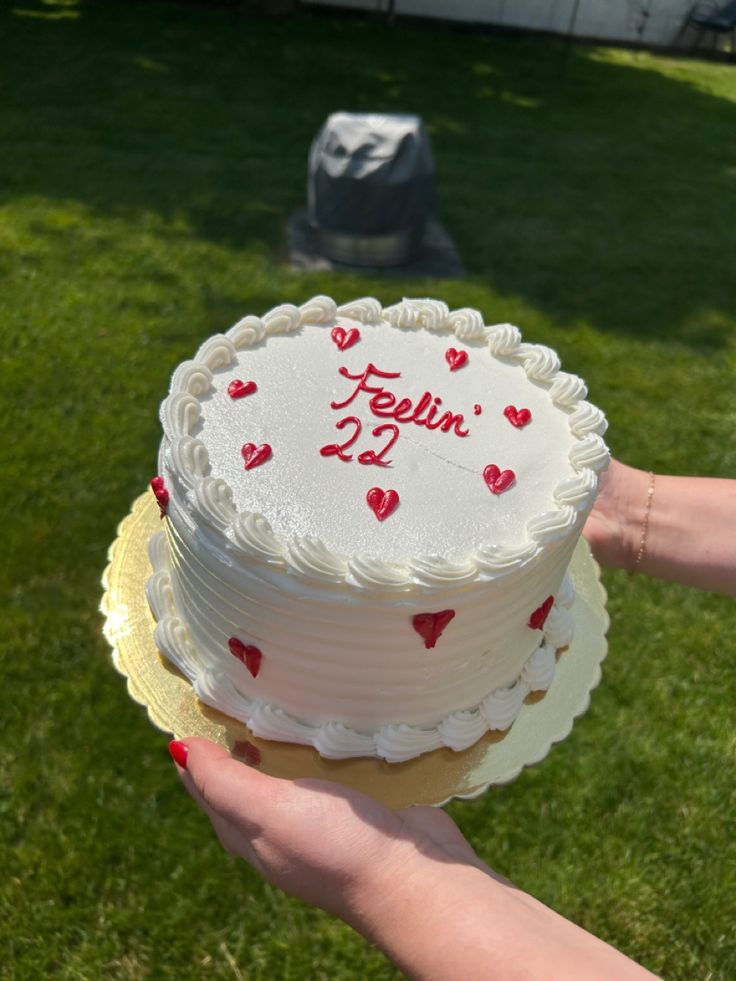 a person holding a cake with hearts on it in their hand and the number twenty two