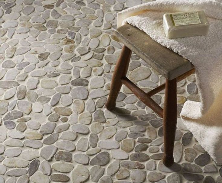 a white towel sitting on top of a wooden chair next to a stone covered floor