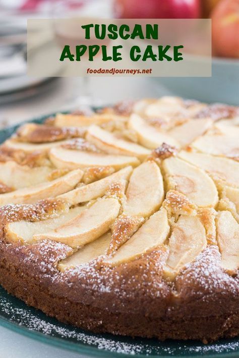 a close up of a cake on a plate with powdered sugar and apples in the background