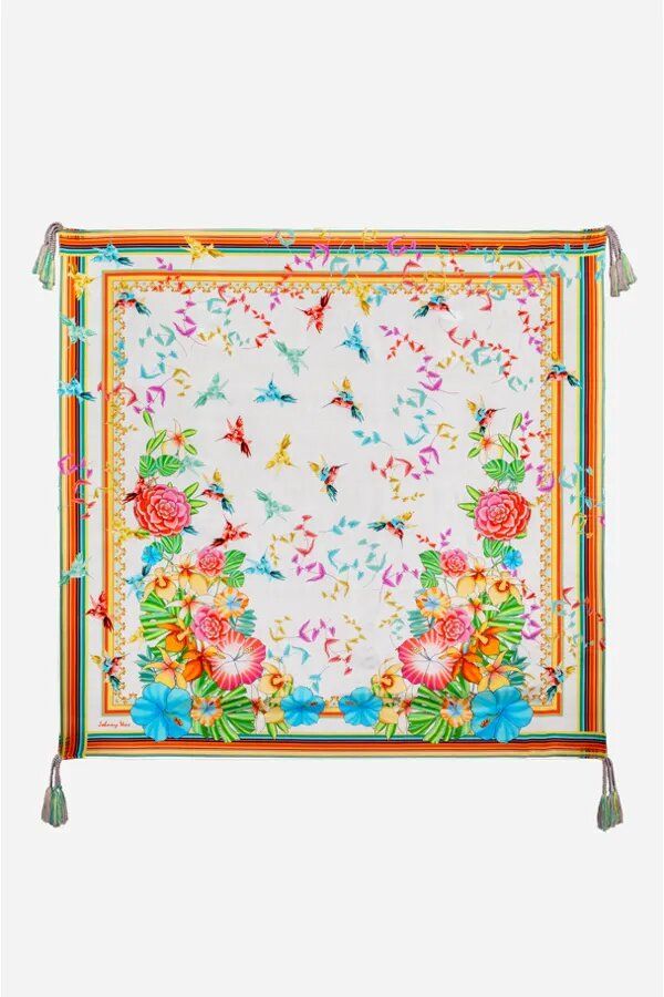 a white square scarf with colorful flowers and birds on the border, hanging from a metal stand