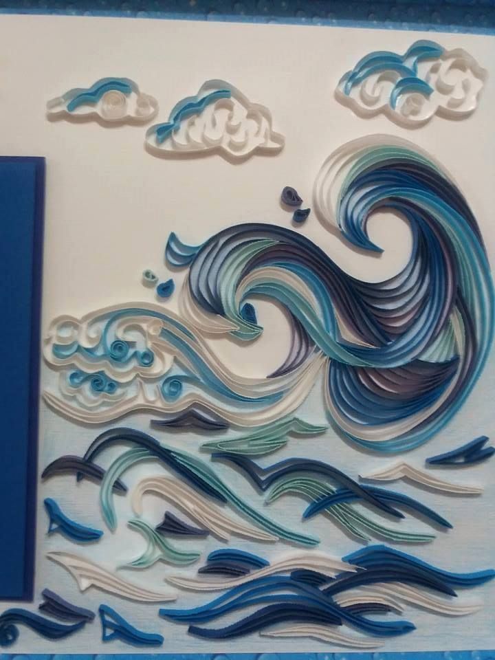 an artistic paper art piece with waves and clouds in blue, white and grey colors