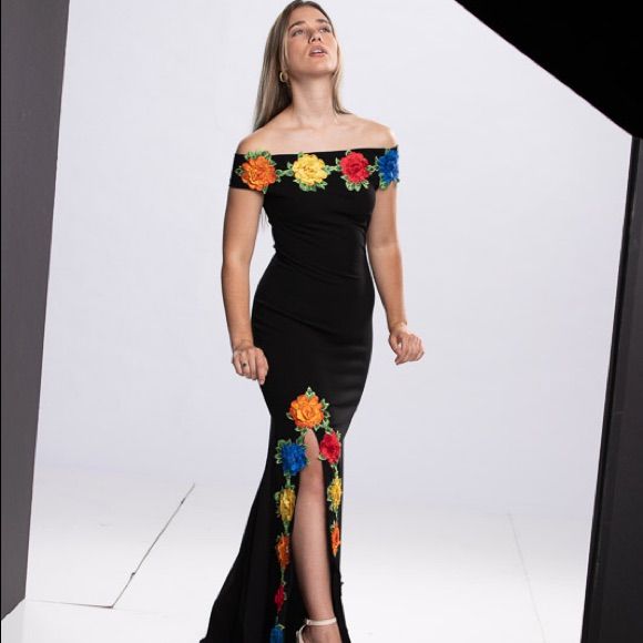 a woman in a black dress with flowers on the side is posing for a photo