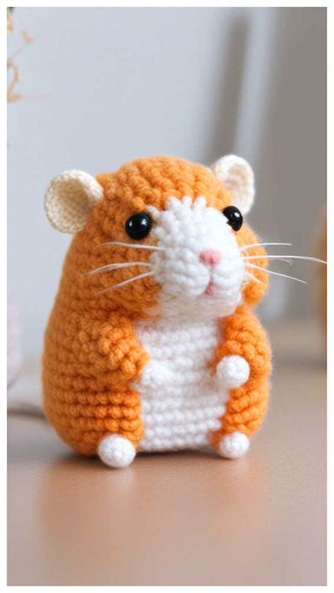 an orange and white crocheted hamster sitting on top of a wooden table