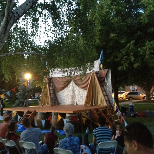 an outdoor stage set up with people sitting in chairs