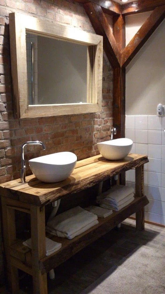 two white bowls sit on a wooden table in front of a brick wall and mirror