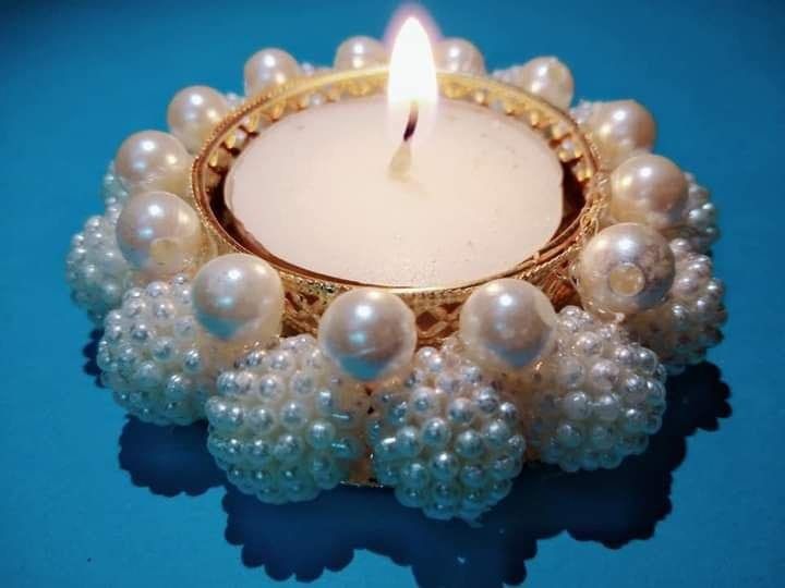 a candle that is sitting in some kind of bowl with pearls on the bottom and around it